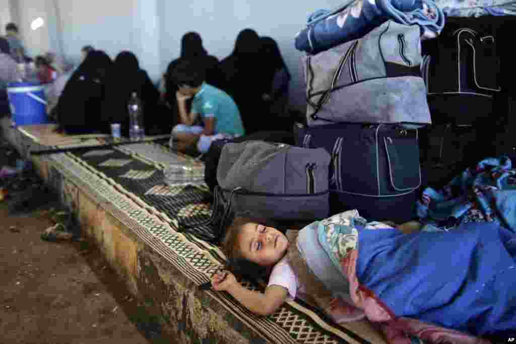 Một bé gái Syria nằm ngũ cạnh hành lý của gia đình tại cửa khẩu Bab Al-Salameh ở Azaz. Gia đình chạy lánh nạn này hy vọng sẽ được vào một trong các trại tị nạn ở Thổ Nhĩ Kỳ, 23/8/12