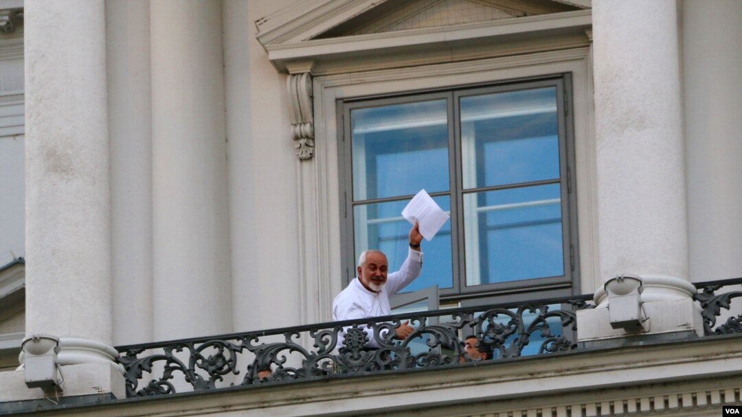 Ngoại trưởng Iran Mohamad Javad Zarif giơ tập tài liệu và nói "Chúng ta vẫn phải làm việc", trên ban công Palais Coburg ở Vienna, nơi diễn ra các cuộc đàm phán hạt nhân, ngày 12/7/2015.